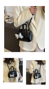 Detailsicht der schwarzen Muscheltasche mit silbernem Schleifenanhänger und Gurt