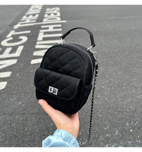 Detail of black mini quilted bag with lychee grain leather and silver chain strap