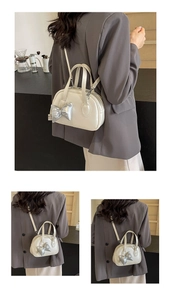 Detail der weißen Boston-Handtasche mit silberner 3D-Schleife und verstellbarem Gurt