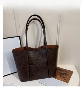 Detail of dark brown tote bag with crocodile texture and long shoulder straps