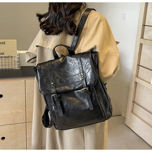 Detailansicht des schwarzen Retro-Rucksacks mit Bronze-Schnalle auf khakifarbenem Trenchcoat