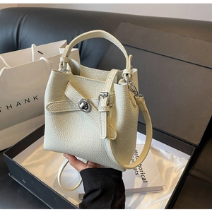 Detailansicht der cremeweißen Eimer-Tasche mit Lychee-Leder, Silber-Drehverschluss