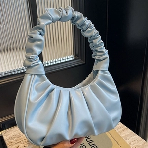 Light blue pleated cloud shoulder bag in crescent shape on marble surface