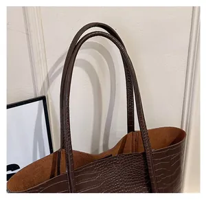 Detail of dark brown croc-embossed tote bag featuring long slim double shoulder straps