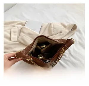 Detail of spacious interior of brown quilted bag with gold chain and essentials