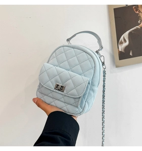 Detail showing mini light blue quilted backpack with silver clasp and chain strap