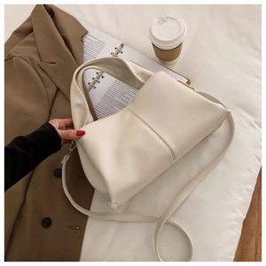 Detail der weißen Handtasche aus Leder mit Lychee-Maserung und goldenen Beschlägen