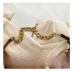 Detail of brown quilted leather bag featuring a gold chain strap and floral logo emblem