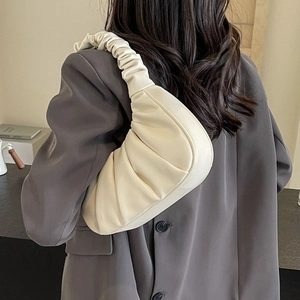 Chic beige ruched cloud hobo bag with pleated shoulder strap worn by a female model