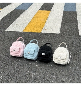Flat lay of four mini quilted backpacks in pink, blue, black, and white colors