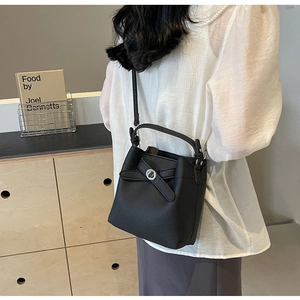 Detail der schwarzen Eimertasche mit Lychee-Muster und silbernem Schloss am Modell