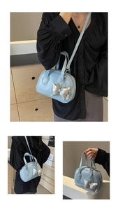 Detailansicht der hellblauen Muschel-Tasche mit glänzendem silbernem Schleifenanhänger