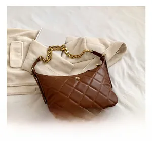 Close-up of brown quilted shoulder bag with gold chain strap on vintage corduroy fabric