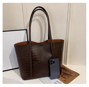 Detailed size comparison of brown crocodile texture tote bag next to a smartphone