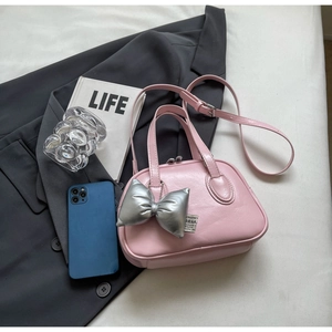 Flachbild von rosa glänzender Muscheltasche mit silbernem Schleifenanhänger und Gurt