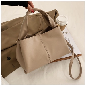 Detail der weichen PU-Lederstruktur der beige Tote-Tasche mit Riemen und Ziernähten