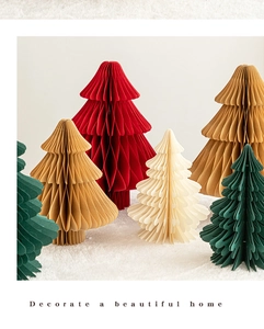 Close-up of paper honeycomb Christmas trees in red, green, and cream on a snowy base