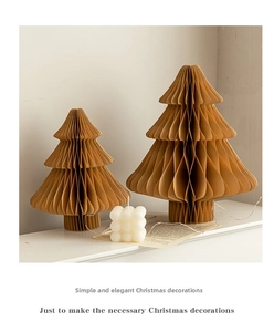Detailed macro view of two honeycomb paper Christmas tree ornaments on white surface