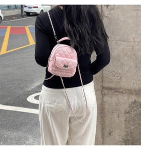 Detailed view of pink quilted mini backpack with silver chain strap worn by a model
