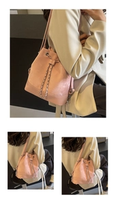 Detailed view of a pink bucket bag featuring a drawstring closure and leather chain straps