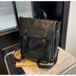 Detail eines schwarzen Vintage-Lederrucksacks mit strukturierter Optik und Messingschnallen