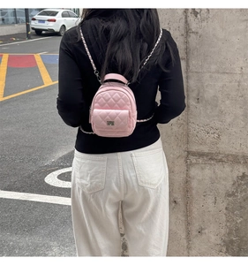 Detail of pink quilted mini backpack with silver chain and turn-lock on a model