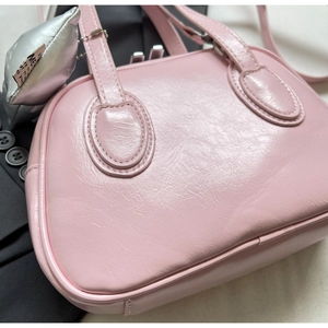 Nahaufnahme einer rosa Handtasche aus glänzendem PU-Leder mit silbernem Anhänger