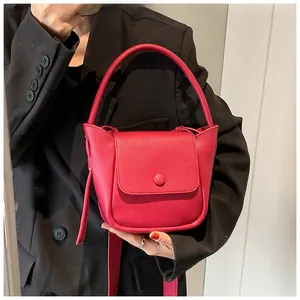 Close-up of red lychee pattern leather bucket bag with top handle and magnetic closure