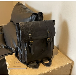Detail eines schwarzen Vintage-Rucksacks mit Ölwachs-Textur und Metallschnallen-Riemen