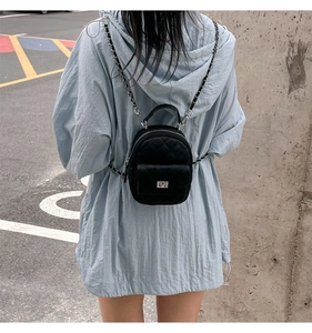 Detailed view of black quilted mini backpack featuring chain straps and metal top handle