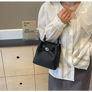 Details der schwarzen Eimer-Handtasche aus genarbtem Leder mit Schleife und Drehverschluss