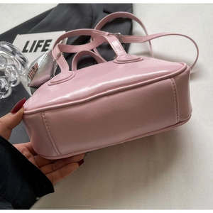 Detail der rosa PU-Leder-Tasche mit glänzender Faltenstruktur und Herz-Anhänger
