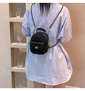 Close-up of black quilted mini backpack with silver twist lock and chain strap