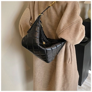 Detail of black quilted shoulder bag featuring gold hardware and elegant chain strap