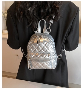 Detail of silver quilted mini backpack on a model showing stylish metal texture and size