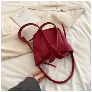 Close-up of deep red lychee pattern leather shoulder bag on a minimalist background