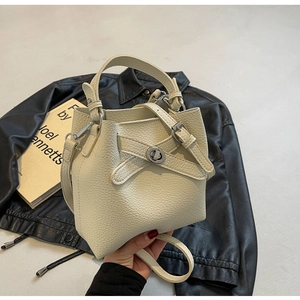 Detailaufnahme der cremefarbenen Beuteltasche aus genarbtem Leder mit silbernem Drehverschluss