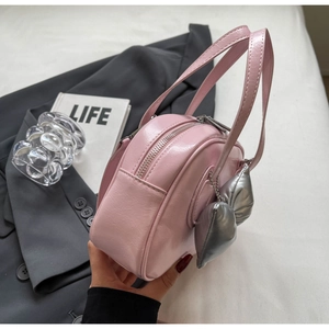 Detailaufnahme der glänzenden rosa Muscheltasche aus Lackleder mit Herzanhänger