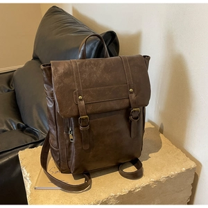 Detailansicht eines dunkelbraunen Retro-Lederrucksacks mit Schnallen auf Steinsockel