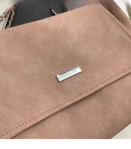 Detail of pink matte leather tote bag with silver MAO JIE logo plaque and chain strap