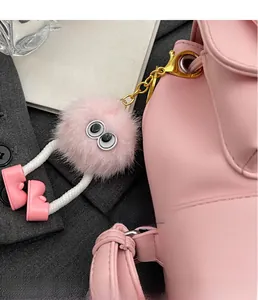 Dettaglio di un portachiavi mostro in peluche rosa con grandi occhi e gancio dorato