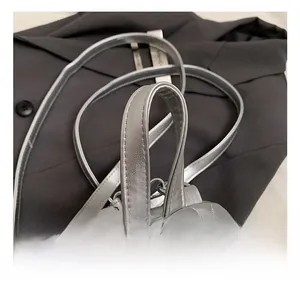 Detail view of silver quilted backpack handle with glossy metallic leather finish