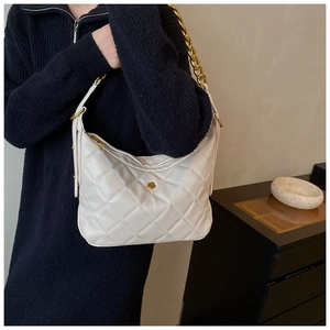 Close-up of quilted white shoulder bag featuring gold camellia hardware and chain strap