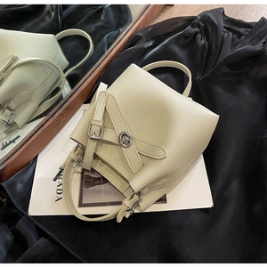 Detailaufnahme einer cremefarbenen Eimer-Tasche aus Leder mit silbernem Drehverschluss