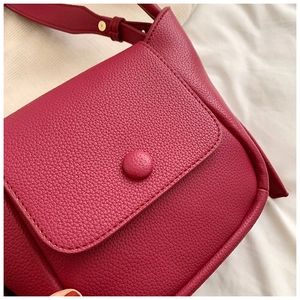 Detail of rose red lychee texture leather bag with gold rivets and flap closure