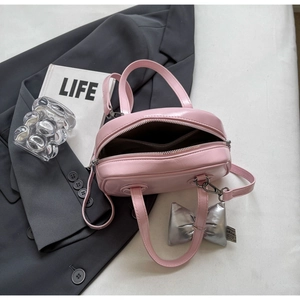Detailansicht einer rosa Muschel-Handtasche mit silbernem Schleifenanhänger und Innenfach
