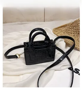 Detail view of black crocodile pattern mini square bag with gold hardware and strap