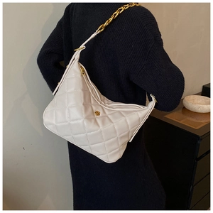 White quilted hobo bag with gold chain strap and floral detail worn by a model