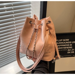 Detail of pink bucket bag with metal chain drawstring and leather shoulder strap
