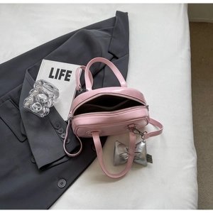 Detail der rosa Handtasche mit silbernem Schleifenanhänger und verstellbarem Riemen